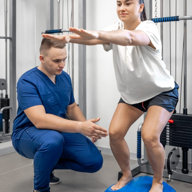 Physiotherapist helping female patient with rehabilitation, balance exercise with bosu ball, woman and doctor during rehab physiotherapy in gym.