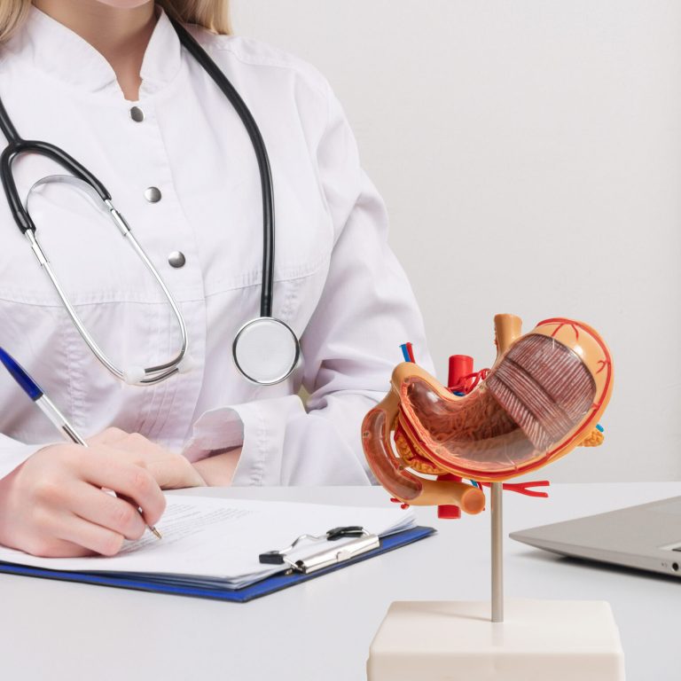 Young beautiful doctor woman working happy and smile in hospital, sitting on table, mockup stomach on work desk,medical concept